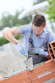 Apprentice of masonry laying bricks