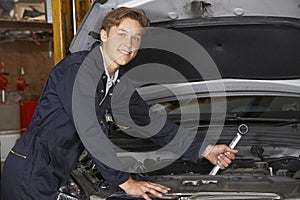 Apprentice Mechanic In Auto Shop Working On Car Engine