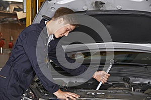 Apprentice Mechanic In Auto Shop Working On Car Engine