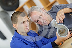 Apprentice mechanic and mentor analyzing broken part