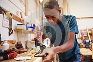 Apprentice Planing Wood In Carpentry Workshop