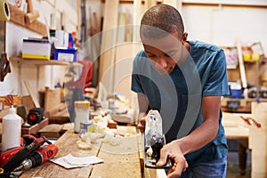 Apprentice Planing Wood In Carpentry Workshop