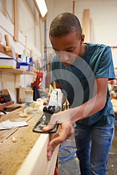 Apprentice Planing Wood In Carpentry Workshop