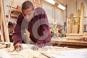 Apprentice Planing Wood In Carpentry Workshop