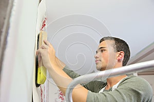 Apprentice putting wallpaper on the wall