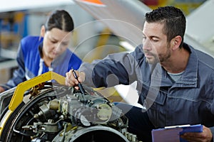 Apprentice studying car engines with mechanic