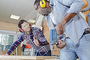 apprentice and teacher drilling wooden plank together