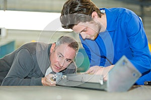 Apprentice working with teacher in metalworks factory