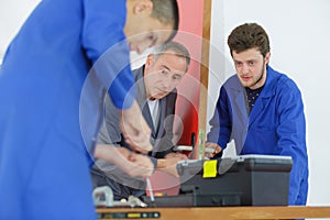 Apprentices learning to fit door mechanism