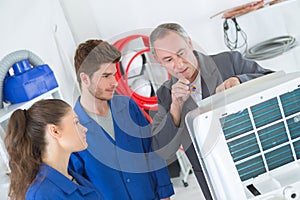 Apprentices learning to repair industrial air conditioning