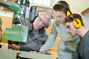 Apprentices learning to use industrial machine