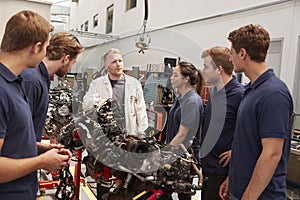 Apprentices studying car engines with a mechanic, close up