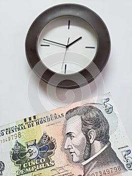 approach to honduran banknote of five lempiras and background with a circular wall clock