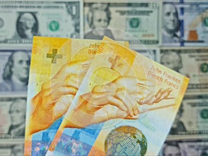 approach to swiss banknotes of ten francs and background with american dollar bills
