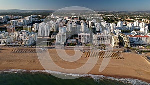 Approaching aerial view of beach, boardwalk and buildings in Quarteira, Algarve, Portugal