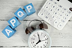 APQP (Advanced Product Quality Planning) text with alarm clock and calculator on wooden background photo