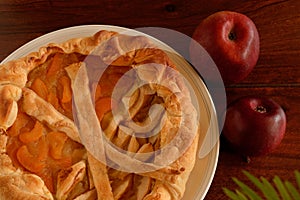 Apricot and apple tart and apples on dark wooden table