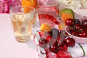 Apricot and cherry juice, apricots, cherries and grapes on a sunny table