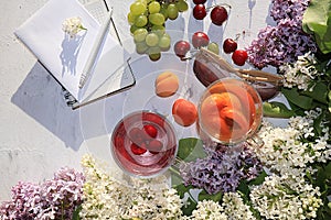 Apricot and cherry juice, apricots, cherries and grapes on a sunny table next to a notebook and copy space, top view.