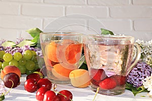 Apricot and cherry juice, apricots, cherries and grapes on a sunny table.