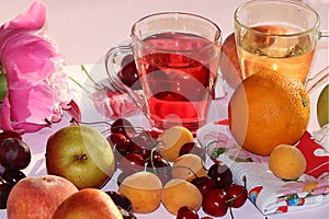 Apricot and cherry juice, apricots, cherries and grapes on a sunny table