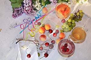 Apricot and cherry juice, apricots, cherries and grapes on a sunny table, top view