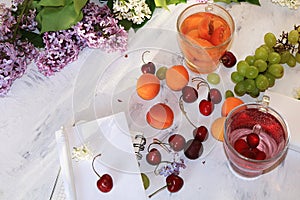 Apricot and cherry juice, apricots, cherries and grapes on a sunny table, top view.