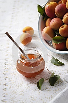 Apricot jam with fresh apricots in the background