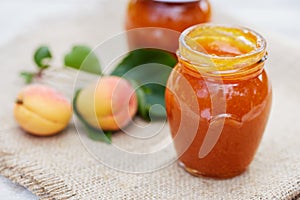 Apricot jam in glass jars with fresh fruit