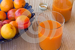 Apricot juice and apricots in a blue vase on white background