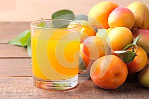 Apricot juice next to fresh apricots on a brown wooden background