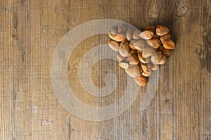 Apricot kernels handful put as heart symbol on wooden background. Food concept with copy space. Product is good for cardio