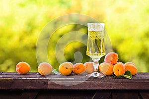 Apricot liqueur and ripe apricots on wooden table