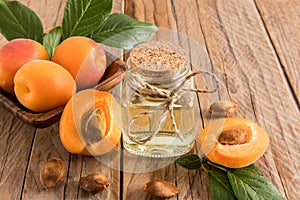 apricot oil in glass bottle on the background of ripe apricots and seeds. wooden background. the concept of rejuvenation