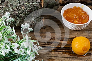 Apricot and peach jam in a small deep dish, sweet orange jam for dessert. Next to a whole fruit, apricots are marinated in syrup.