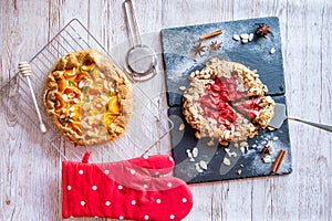 Apricot and strawberry galette placed on wooden table with cooking tools on the side