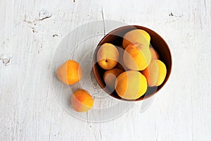 Apricots in a clay bowl on a white wooden background. Still life in a rustic style.