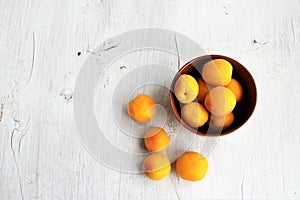 Apricots in a clay bowl on a white wooden background. Still life in a rustic style.
