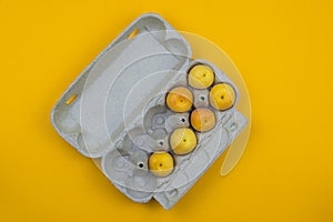 Apricots are in the egg Box on a yellow background.