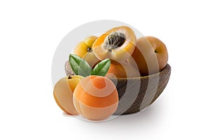 Apricots with leaves isolated on white background. Various fresh summer fruits. Apricots in a wooden bowl. Ripe apricots with copy