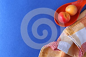 Apricots, orange saucer and towel on a blue background with place for text.