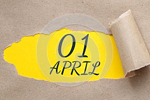 April 01. 01th day of the month, calendar date. Hole in paper with edges torn off. Yellow background is visible through