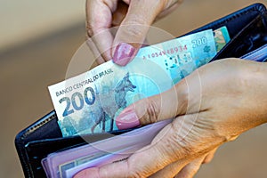 April 19, 2024, Brazil. A woman keeps a 200 (two hundred) reais note in her wallet