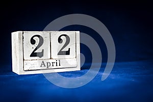 April 22nd, Twenty-second of April, Day 22 of month April - rustic wooden white calendar blocks on dark blue background with empty