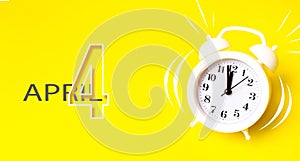 April 4th. Day 4 of month, Calendar date. White alarm clock  with calendar day on yellow background. Minimalistic concept of time