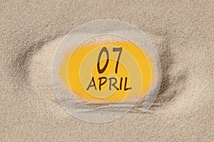 April 7. 7th day of the month, calendar date. Hole in sand. Yellow background is visible through hole