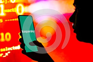 April 27, 2022, Brazil. In this photo illustration, a silhouetted woman holds a smartphone with the Kaspersky Lab logo displayed