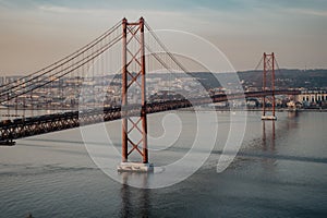 `25 of April` Bridge over tagus river at sunset in Lisbon, Portugal. View from Sanctuary of Christ the King `Cristo Rei