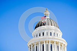 April 14, 2018 Sacramento / CA / USA - The US and the California state flag waving in the wind in front of the dome of the