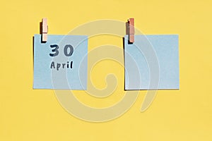 April 30st. Day of 30 month, calendar date. Two blue sheets for writing on a yellow background. Top view, copy space. Spring month photo